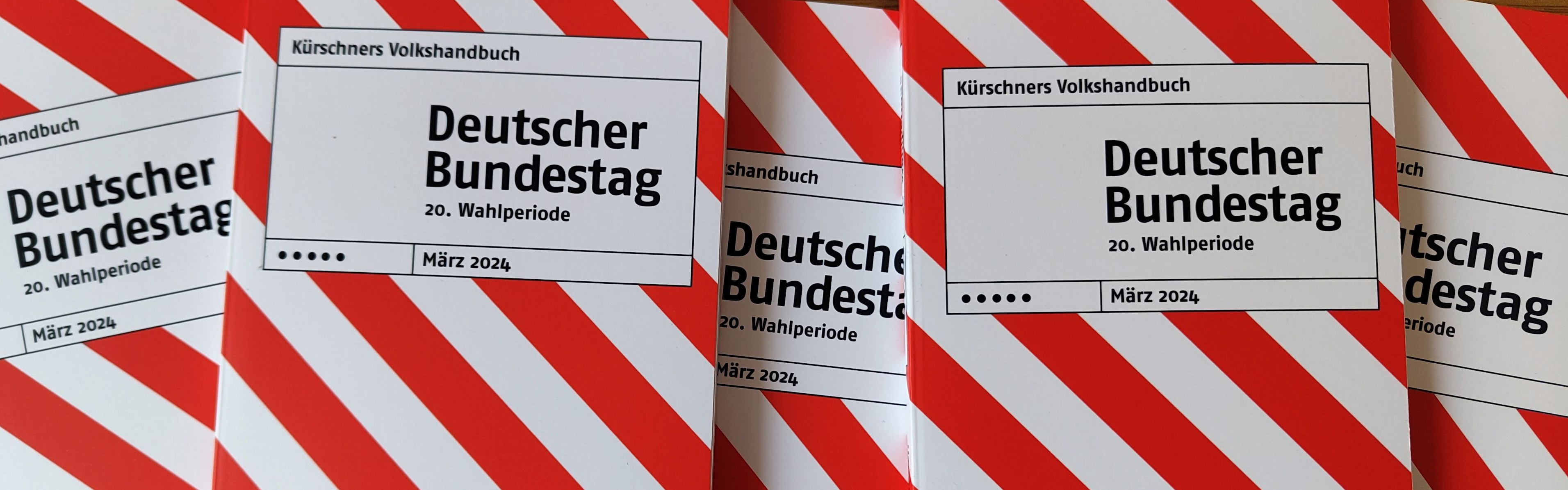 Mehrere nebeneinander liegende Exemplare des rot-weiß gestreiften Taschenbuchs "Kürschners Volkshandbuch Deutscher Bundestag".